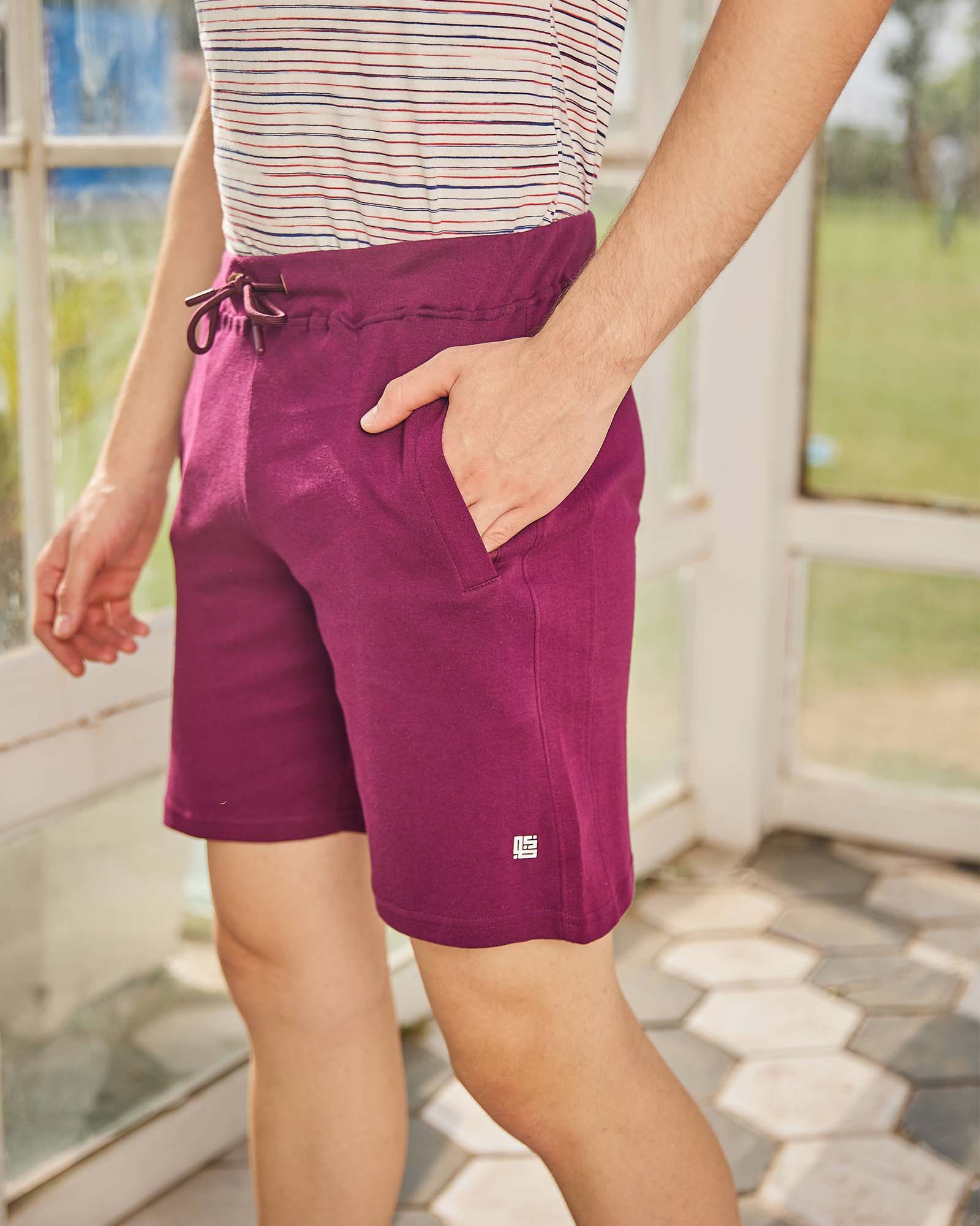 Person wearing purple shorts with a small logo, standing outdoors.